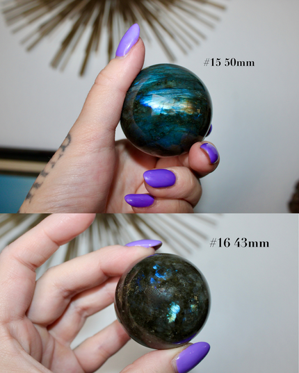 Two views of a hand holding a shiny, reflective labradorite sphere with measurements indicated.