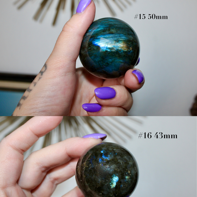 Two views of a hand holding a shiny, reflective labradorite sphere with measurements indicated.