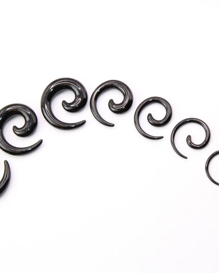 A pair of sleek, black acrylic spiral taper earrings displayed on a clean, neutral surface. The spirals curve smoothly in a bold, symmetrical design, tapering to fine points at the ends. Their glossy finish reflects light subtly, emphasizing their smooth texture and modern, minimalist style. Sized for stretched ears, the earrings showcase a striking balance of simplicity and statement, perfect for alternative or gauged jewelry wearers.