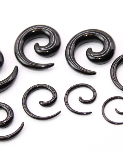 A pair of sleek, black acrylic spiral taper earrings displayed on a clean, neutral surface. The spirals curve smoothly in a bold, symmetrical design, tapering to fine points at the ends. Their glossy finish reflects light subtly, emphasizing their smooth texture and modern, minimalist style. Sized for stretched ears, the earrings showcase a striking balance of simplicity and statement, perfect for alternative or gauged jewelry wearers.
