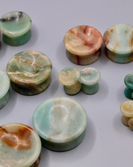 A beautiful pair of Natural Calcite stone plugs, hand-carved and polished into a smooth double flare shape for a secure and comfortable fit. These ear gauges showcase the soft, luminous quality of calcite, with creamy whites, warm honey tones, and subtle translucency that varies from piece to piece. Each plug highlights unique natural banding and organic patterns, making every pair one-of-a-kind.
