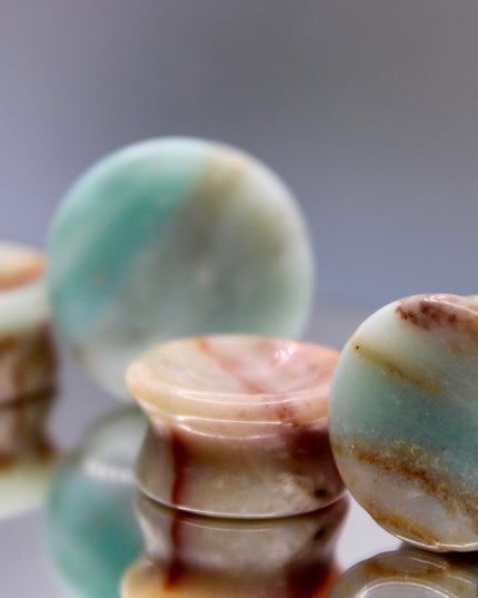 A beautiful pair of Natural Calcite stone plugs, hand-carved and polished into a smooth double flare shape for a secure and comfortable fit. These ear gauges showcase the soft, luminous quality of calcite, with creamy whites, warm honey tones, and subtle translucency that varies from piece to piece. Each plug highlights unique natural banding and organic patterns, making every pair one-of-a-kind.