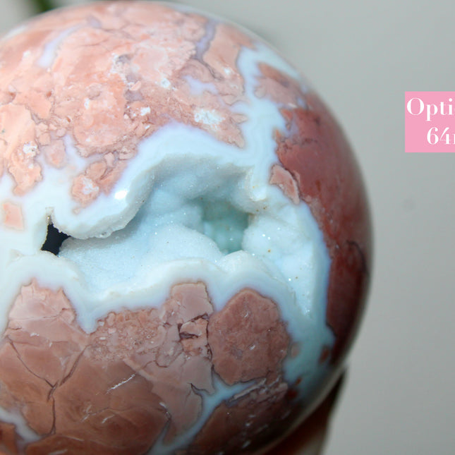 Elevate your space with the calming beauty and gentle energy of this hand-polished Flower Agate Sphere, a natural work of art that inspires peace, growth, and intention. Featuring dreamy shades of soft pink, creamy white, and warm peach, each sphere showcases unique floral-like inclusions that resemble delicate blooms suspended within the stone—making every piece truly one of a kind.