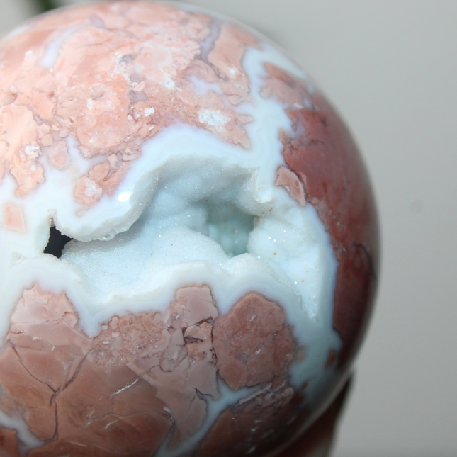 Elevate your space with the calming beauty and gentle energy of this hand-polished Flower Agate Sphere, a natural work of art that inspires peace, growth, and intention. Featuring dreamy shades of soft pink, creamy white, and warm peach, each sphere showcases unique floral-like inclusions that resemble delicate blooms suspended within the stone—making every piece truly one of a kind.