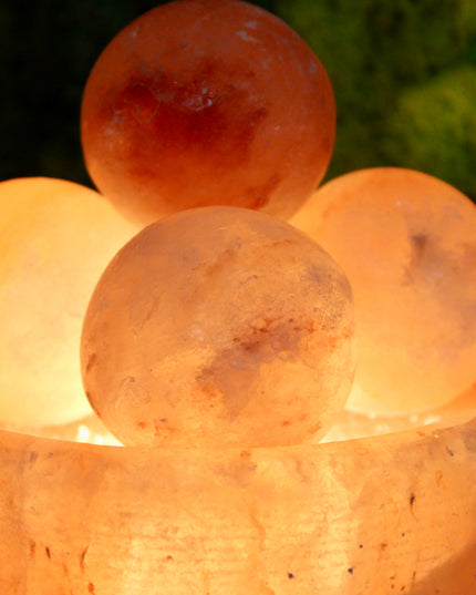 An extra-large Himalayan Salt Lamp featuring a handcrafted, bowl-shaped salt crystal base filled with smooth, removable Himalayan salt massage balls. The lamp emits a warm, amber glow that creates a calming ambiance, perfect for relaxation, meditation, or bedroom lighting. Each massage ball is made from the same high-quality pink salt and can be used warm for soothing sore muscles or kept in the bowl for a decorative touch.