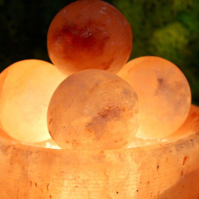 An extra-large Himalayan Salt Lamp featuring a handcrafted, bowl-shaped salt crystal base filled with smooth, removable Himalayan salt massage balls. The lamp emits a warm, amber glow that creates a calming ambiance, perfect for relaxation, meditation, or bedroom lighting. Each massage ball is made from the same high-quality pink salt and can be used warm for soothing sore muscles or kept in the bowl for a decorative touch.