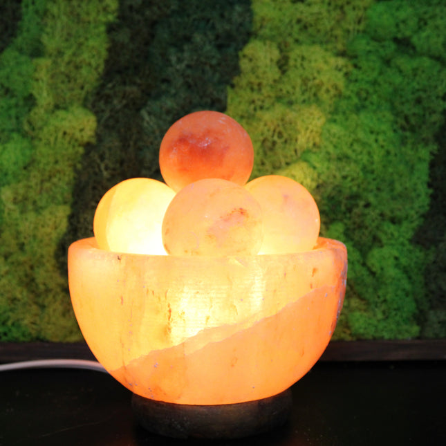An extra-large Himalayan Salt Lamp featuring a handcrafted, bowl-shaped salt crystal base filled with smooth, removable Himalayan salt massage balls. The lamp emits a warm, amber glow that creates a calming ambiance, perfect for relaxation, meditation, or bedroom lighting. Each massage ball is made from the same high-quality pink salt and can be used warm for soothing sore muscles or kept in the bowl for a decorative touch.