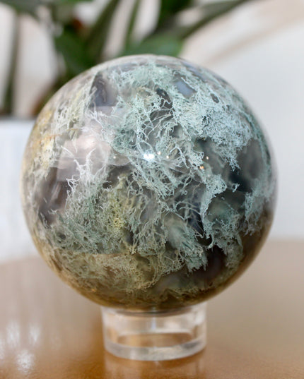 This XL Moss Agate Sphere features a stunning mix of natural green inclusions and cloudy white tones, reminiscent of forest landscapes or underwater gardens. Each sphere is one of a kind, with swirling patterns and depth that make it a true conversation piece.