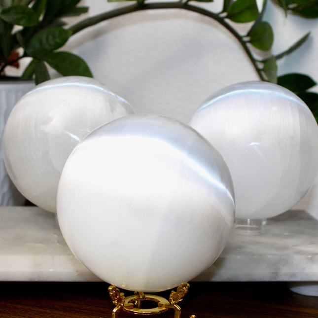 This XL Selenite Sphere showcases the luminous beauty of satin spar with its clean white tone and smooth, polished surface. Its generous size and soft glow make it a striking centerpiece for any space.