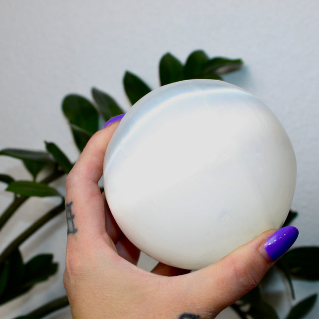 This XL Selenite Sphere showcases the luminous beauty of satin spar with its clean white tone and smooth, polished surface. Its generous size and soft glow make it a striking centerpiece for any space.