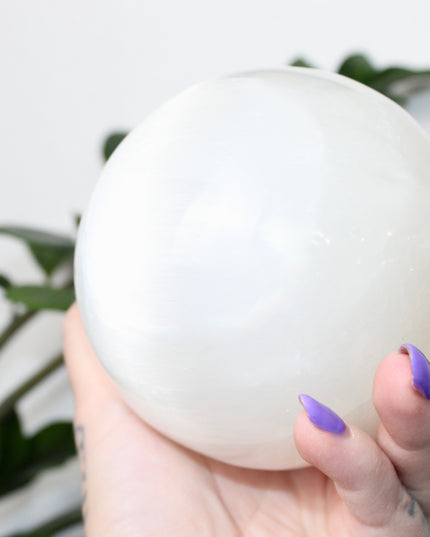This XL Selenite Sphere showcases the luminous beauty of satin spar with its clean white tone and smooth, polished surface. Its generous size and soft glow make it a striking centerpiece for any space.