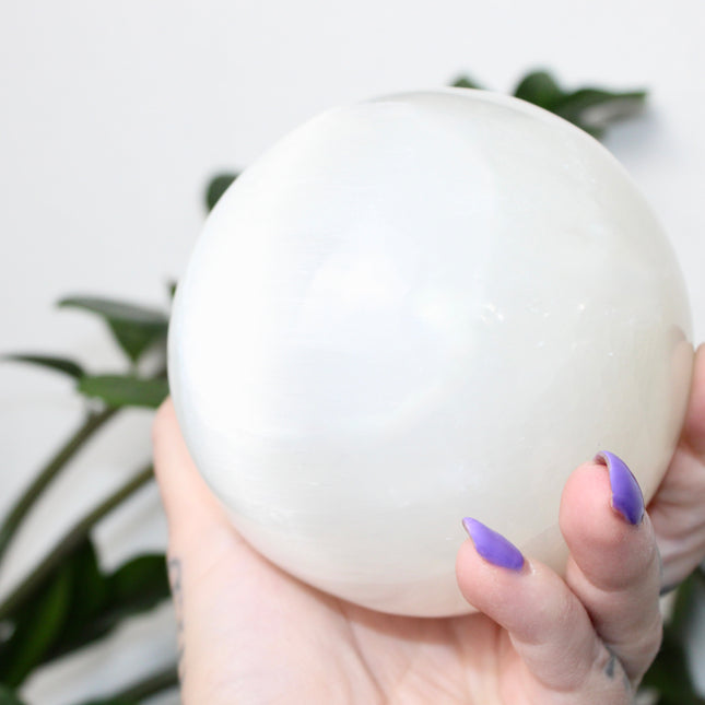This XL Selenite Sphere showcases the luminous beauty of satin spar with its clean white tone and smooth, polished surface. Its generous size and soft glow make it a striking centerpiece for any space.