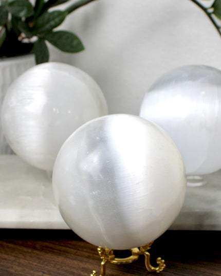 This XL Selenite Sphere showcases the luminous beauty of satin spar with its clean white tone and smooth, polished surface. Its generous size and soft glow make it a striking centerpiece for any space.