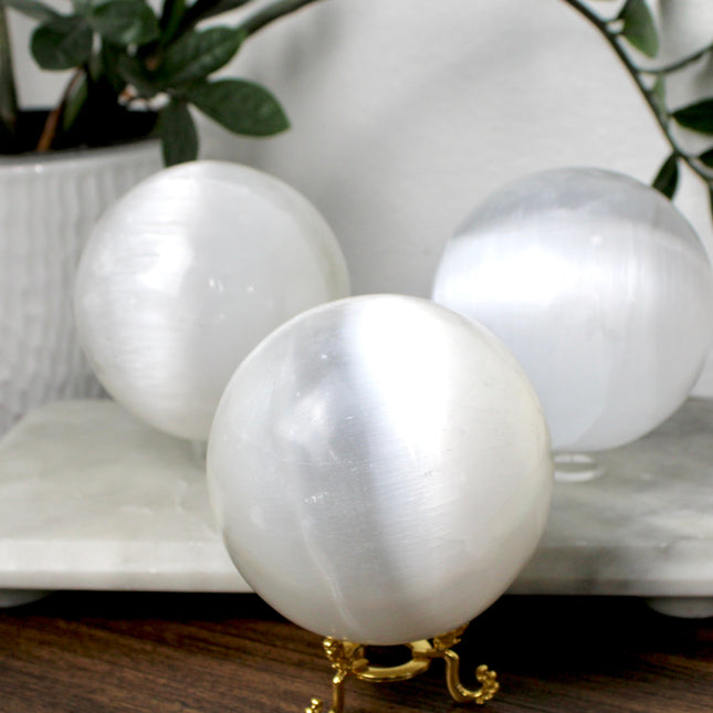 This XL Selenite Sphere showcases the luminous beauty of satin spar with its clean white tone and smooth, polished surface. Its generous size and soft glow make it a striking centerpiece for any space.