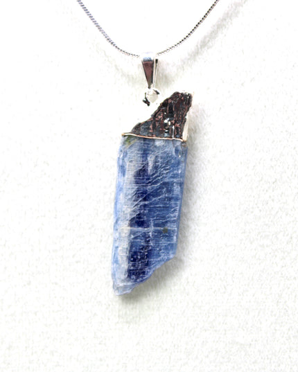 This handmade Blue Kyanite necklace features a raw, unpolished stone that highlights the natural striations and shimmer of the mineral. Set on a sleek silver-tone chain, the pendant offers a minimalist, earthy aesthetic perfect for everyday wear or adding a unique touch to layered outfits.