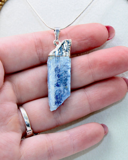 This handmade Blue Kyanite necklace features a raw, unpolished stone that highlights the natural striations and shimmer of the mineral. Set on a sleek silver-tone chain, the pendant offers a minimalist, earthy aesthetic perfect for everyday wear or adding a unique touch to layered outfits.