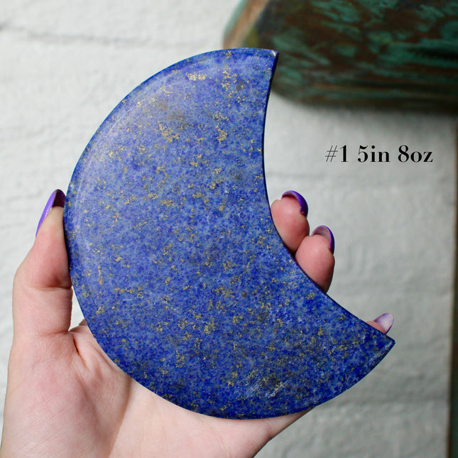 Crescent-shaped blue lapis held by a hand with text indicating size and option.