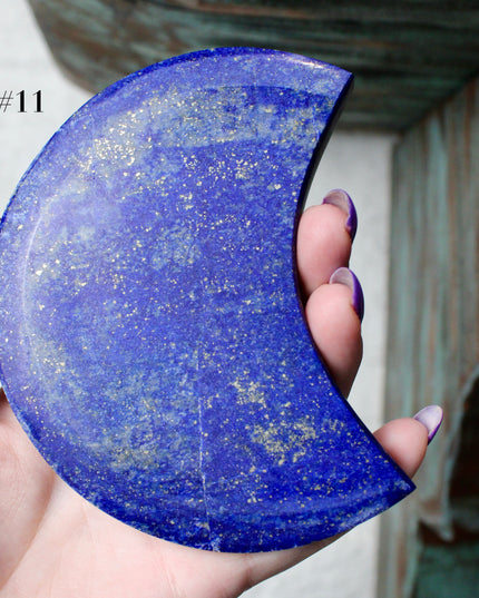 Crescent-shaped blue lapis held by a hand with text indicating size and option.