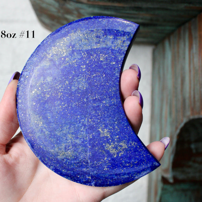 Crescent-shaped blue lapis held by a hand with text indicating size and option.