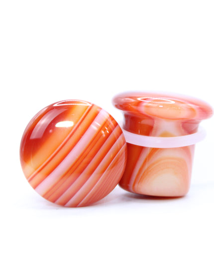 These single flare plugs are carved from genuine Carnelian Agate, showcasing warm, fiery hues and occasional natural banding or translucent zones. Hand-polished to a sleek finish, each plug is smooth and comfortable for everyday wear.