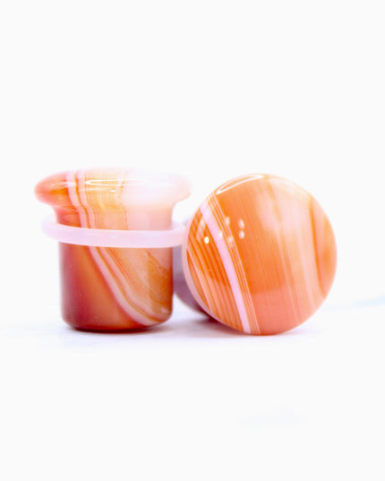 These single flare plugs are carved from genuine Carnelian Agate, showcasing warm, fiery hues and occasional natural banding or translucent zones. Hand-polished to a sleek finish, each plug is smooth and comfortable for everyday wear.