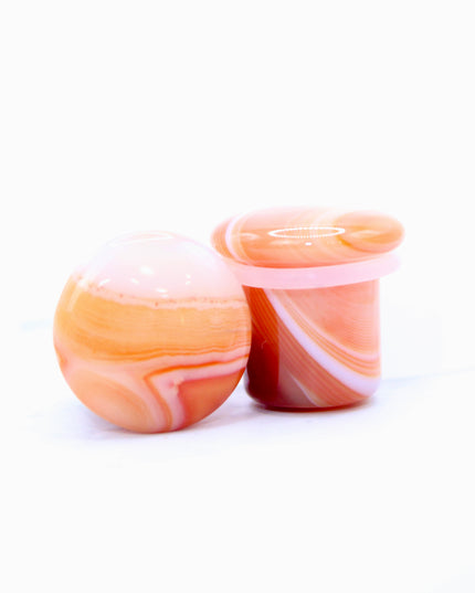 These single flare plugs are carved from genuine Carnelian Agate, showcasing warm, fiery hues and occasional natural banding or translucent zones. Hand-polished to a sleek finish, each plug is smooth and comfortable for everyday wear.