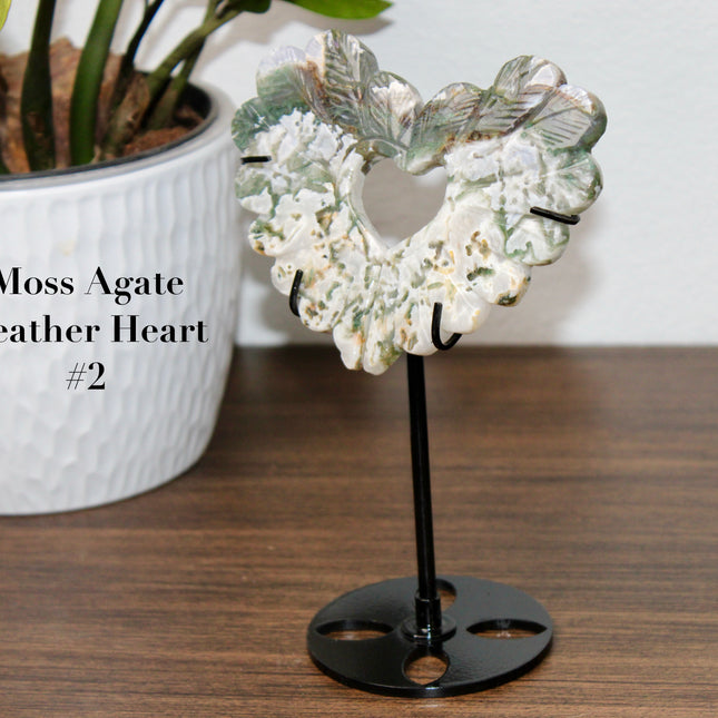 Bring nature’s elegance into your space with this one-of-a-kind Moss Agate Heart Feather Carving on Stand. Each piece is intricately carved into a heart-shaped feather design, capturing soft, organic curves that symbolize both love and lightness. Made from genuine Moss Agate, these carvings showcase lush, forest-like inclusions of deep green within a translucent to milky white base—every piece with its own unique pattern, just like nature intended.