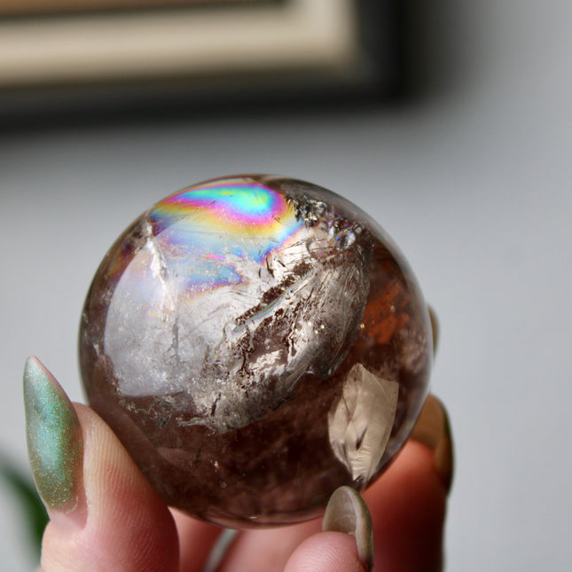 High grade genuine smoky quartz crystal sphere with natural clarity in deep translucent brown to smoky gray tones, hand-polished and displayed on a sturdy silver stand – grounding crystal for meditation, energy clearing, and root chakra healing