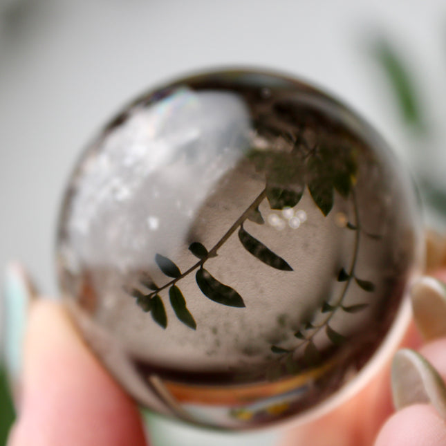 High grade genuine smoky quartz crystal sphere with natural clarity in deep translucent brown to smoky gray tones, hand-polished and displayed on a sturdy silver stand – grounding crystal for meditation, energy clearing, and root chakra healing