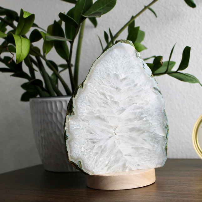 Geode lamp on a wooden surface with a plant and clock in the background