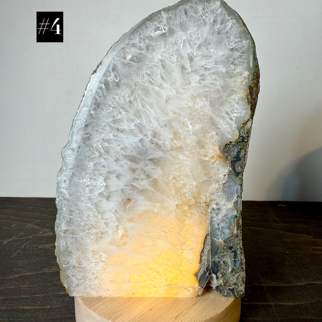 Crystal rock lamp on a wooden base with a soft glow against a neutral background