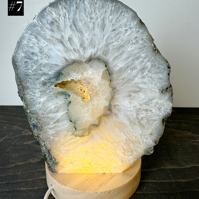 Geode-shaped lamp with wooden base on a dark surface