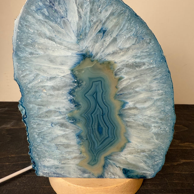 Geode crystal on a wooden stand against a beige background