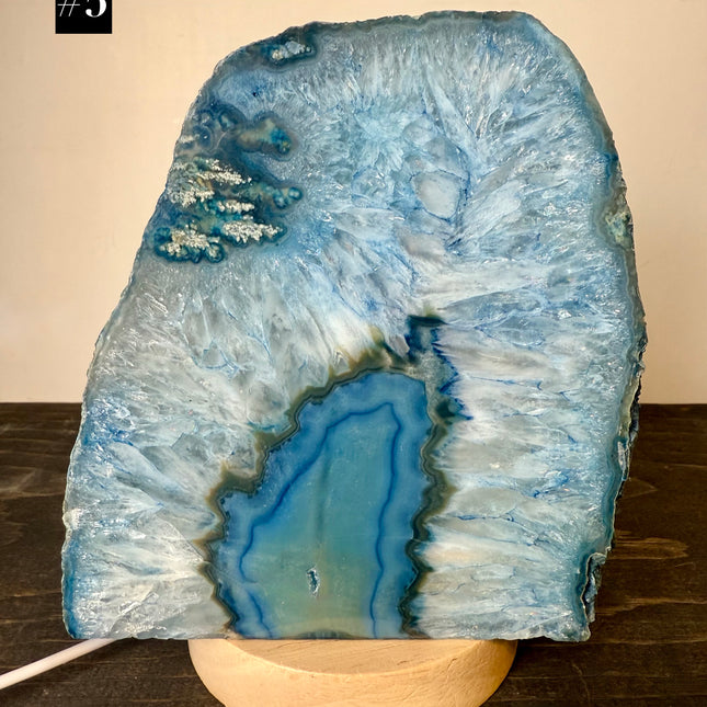 Blue agate stone lamp on a wooden base against a beige wall.