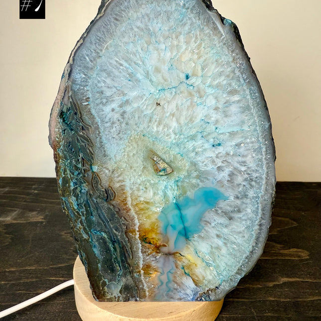 Geode agate blue lamp with wooden base on a dark surface