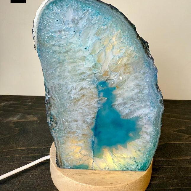 Geode agate lamp with a wooden base on a dark surface