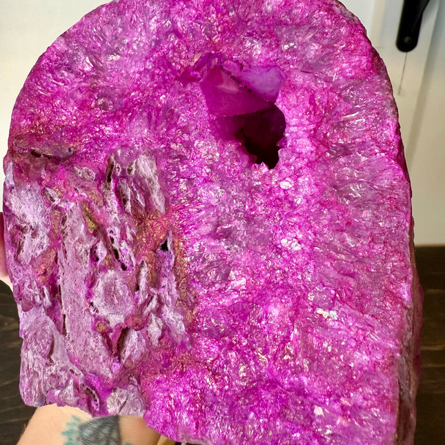 Large pink crystal with a person's arm and tattoo visible at the bottom.