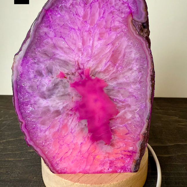 Geode-shaped lamp with pink interior on a wooden base