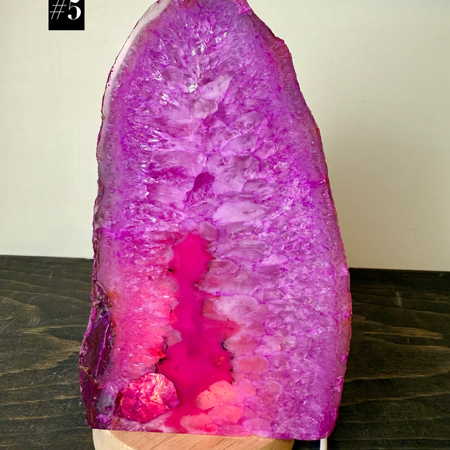 Pink crystal lamp with wooden base on a dark surface