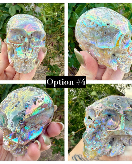 A mesmerizing Genuine Quartz Skull Carving with Rainbow Aura Treatment glows with an ethereal spectrum of colors, resting against a dark, reflective surface. The quartz base is expertly carved into a detailed skull, complete with defined features and a polished finish. The surface shimmers with iridescent hues—vivid blues, purples, pinks, and golds—created through the rainbow aura treatment, a process that bonds precious metals to the quartz for a permanent, luminous effect.