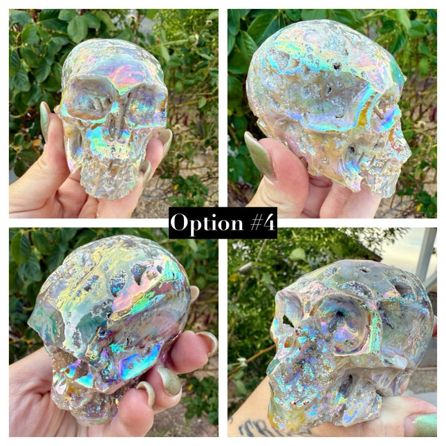A mesmerizing Genuine Quartz Skull Carving with Rainbow Aura Treatment glows with an ethereal spectrum of colors, resting against a dark, reflective surface. The quartz base is expertly carved into a detailed skull, complete with defined features and a polished finish. The surface shimmers with iridescent hues—vivid blues, purples, pinks, and golds—created through the rainbow aura treatment, a process that bonds precious metals to the quartz for a permanent, luminous effect.
