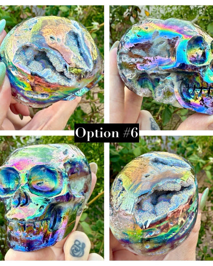 A mesmerizing Genuine Quartz Skull Carving with Rainbow Aura Treatment glows with an ethereal spectrum of colors, resting against a dark, reflective surface. The quartz base is expertly carved into a detailed skull, complete with defined features and a polished finish. The surface shimmers with iridescent hues—vivid blues, purples, pinks, and golds—created through the rainbow aura treatment, a process that bonds precious metals to the quartz for a permanent, luminous effect.