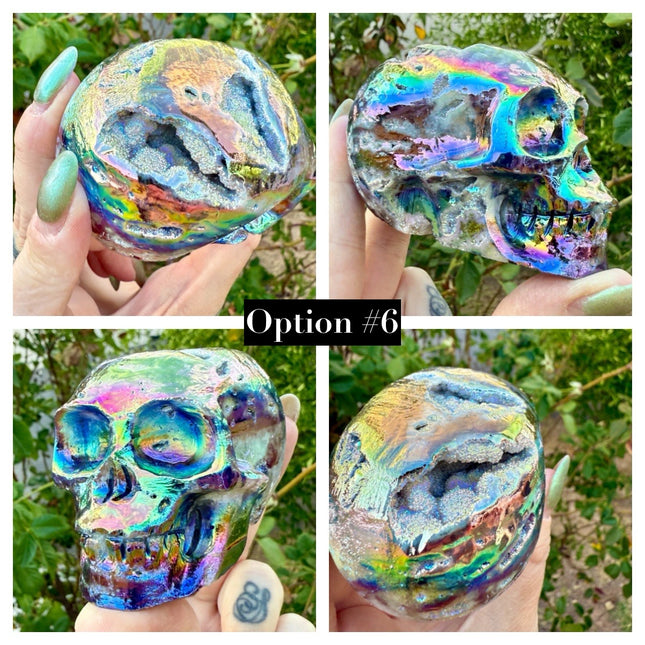 A mesmerizing Genuine Quartz Skull Carving with Rainbow Aura Treatment glows with an ethereal spectrum of colors, resting against a dark, reflective surface. The quartz base is expertly carved into a detailed skull, complete with defined features and a polished finish. The surface shimmers with iridescent hues—vivid blues, purples, pinks, and golds—created through the rainbow aura treatment, a process that bonds precious metals to the quartz for a permanent, luminous effect.
