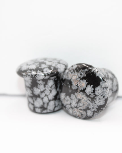 These Snowflake Obsidian Double Flared Plugs feature a smooth, polished surface with natural gray-white crystal "snowflakes" scattered across a rich black volcanic glass base. The double flare ensures a secure, comfortable fit for stretched ears without the need for O-rings. Each pair is uniquely patterned, showcasing the stone’s natural beauty and grounding energy. Durable and stylish, these plugs add a bold yet refined touch to any stretched ear jewelry collection.