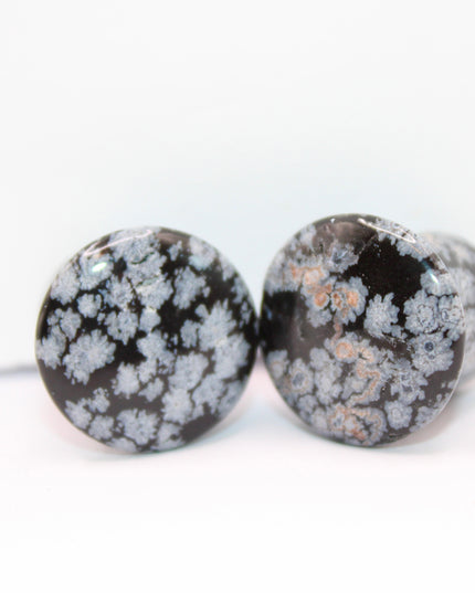 These Snowflake Obsidian Double Flared Plugs feature a smooth, polished surface with natural gray-white crystal "snowflakes" scattered across a rich black volcanic glass base. The double flare ensures a secure, comfortable fit for stretched ears without the need for O-rings. Each pair is uniquely patterned, showcasing the stone’s natural beauty and grounding energy. Durable and stylish, these plugs add a bold yet refined touch to any stretched ear jewelry collection.