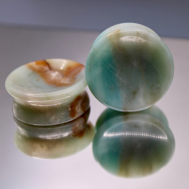 A beautiful pair of Natural Calcite stone plugs, hand-carved and polished into a smooth double flare shape for a secure and comfortable fit. These ear gauges showcase the soft, luminous quality of calcite, with creamy whites, warm honey tones, and subtle translucency that varies from piece to piece. Each plug highlights unique natural banding and organic patterns, making every pair one-of-a-kind.