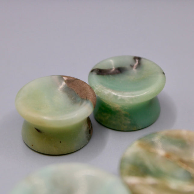 A beautiful pair of Natural Calcite stone plugs, hand-carved and polished into a smooth double flare shape for a secure and comfortable fit. These ear gauges showcase the soft, luminous quality of calcite, with creamy whites, warm honey tones, and subtle translucency that varies from piece to piece. Each plug highlights unique natural banding and organic patterns, making every pair one-of-a-kind.