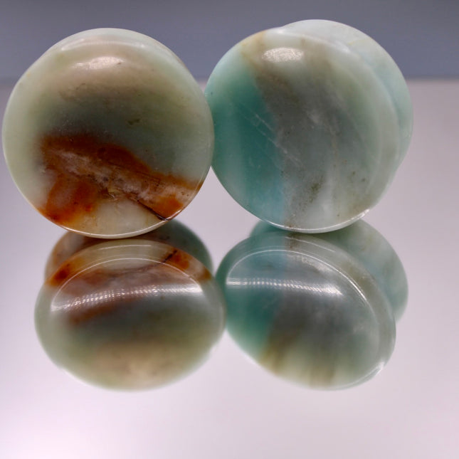 A beautiful pair of Natural Calcite stone plugs, hand-carved and polished into a smooth double flare shape for a secure and comfortable fit. These ear gauges showcase the soft, luminous quality of calcite, with creamy whites, warm honey tones, and subtle translucency that varies from piece to piece. Each plug highlights unique natural banding and organic patterns, making every pair one-of-a-kind.
