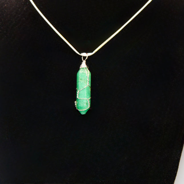 Green pendant necklace on a black stand with a white background