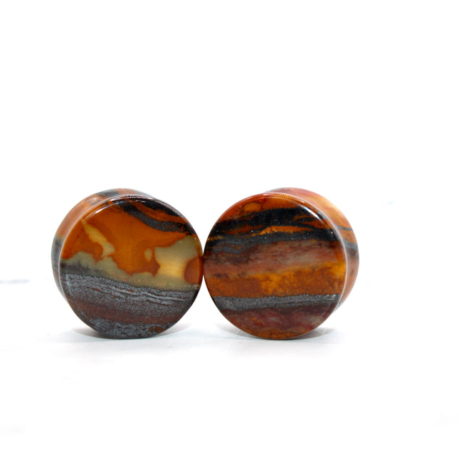 Set of sunset jade earplugs with banded pattern on a white background